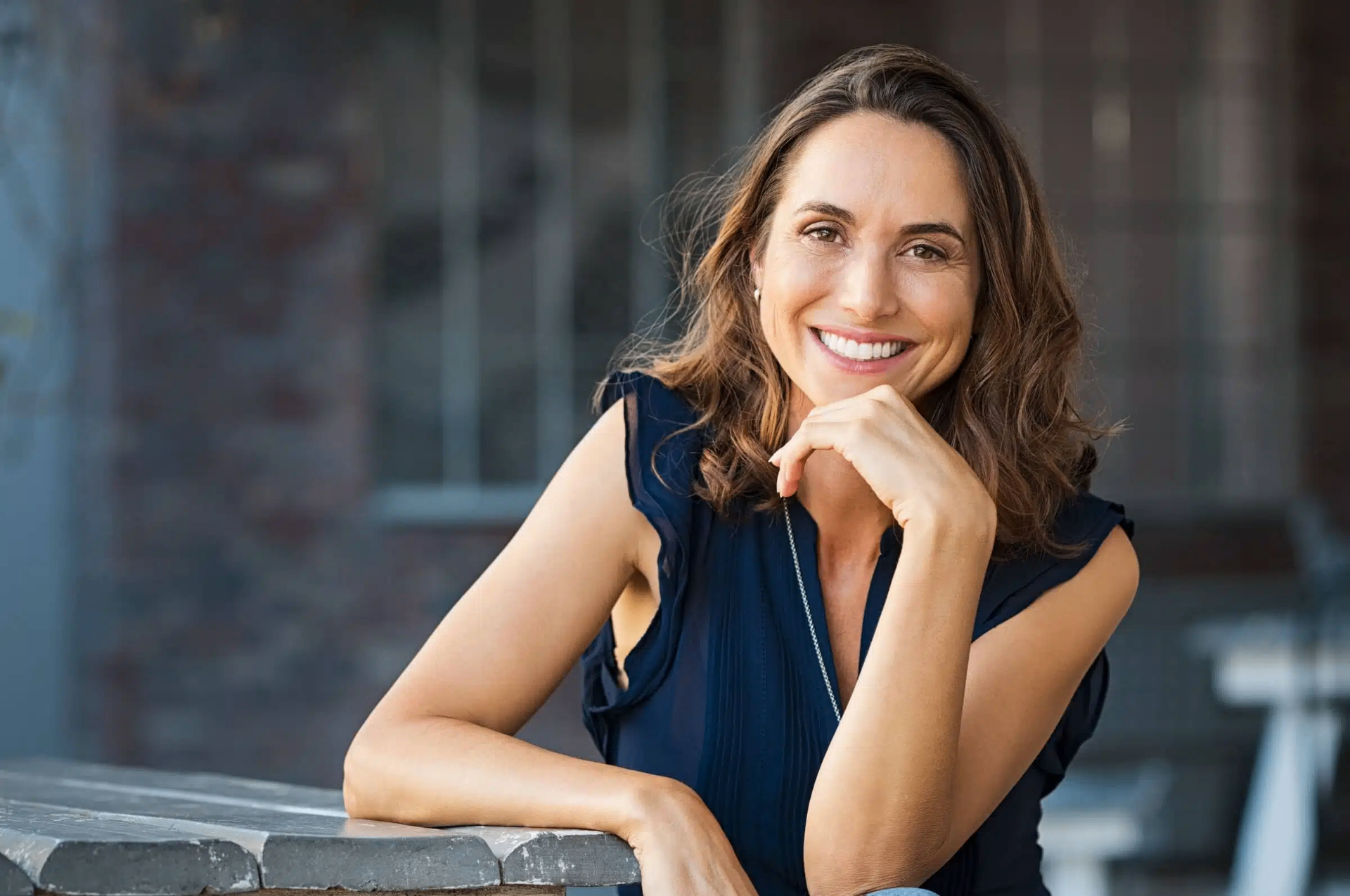 A warm, confident woman smiling thoughtfully — reflecting on changes in her body and seeking answers about her hormone health.