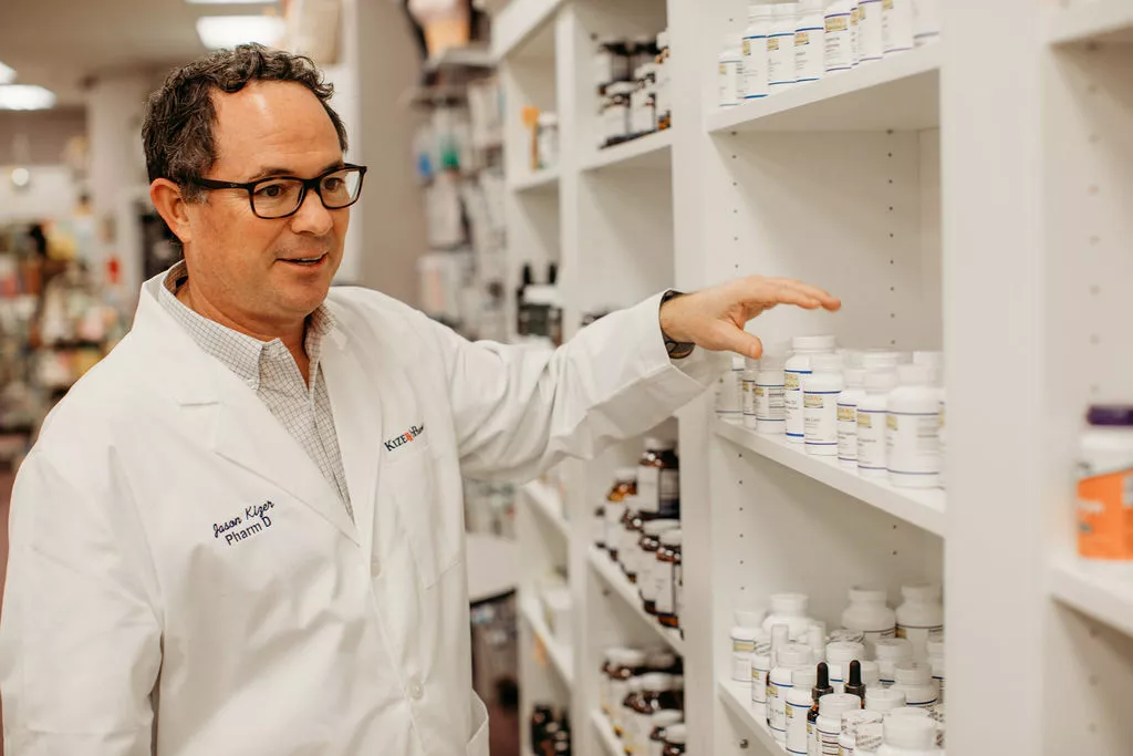 Dr. Jason Kizer, PharmD, reviewing compounded medications on the pharmacy shelves at Kizer Wellness Pharmacy